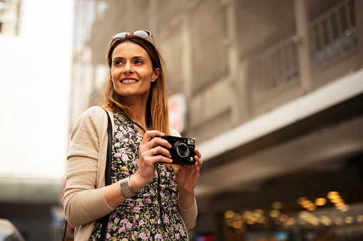 Attractive tourist with a camera. Beautiful woman with camera taking photos of beautiful location