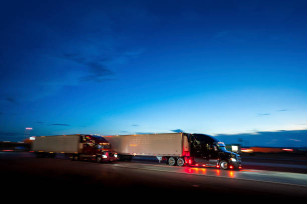 Two semi-truck with container trailers speeding at night in Texas - panning motion blur