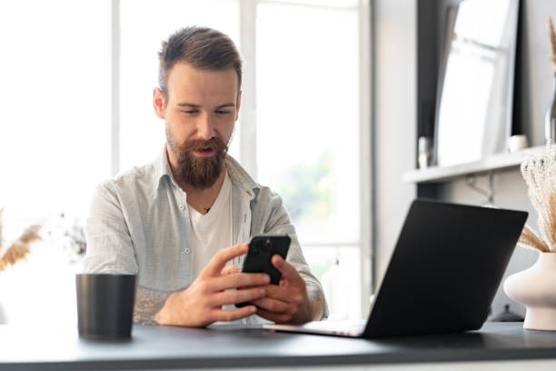 istock Handsome young bearded man spending time at home with phone in hands. 1427469068