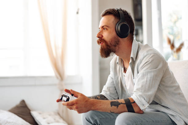 istock Young bearded man playing video games while sitting on the couch at home 1427469203
