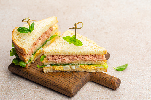 Tuna sandwiches with boiled egg, mayonnaise, lettuce on a wooden board.
