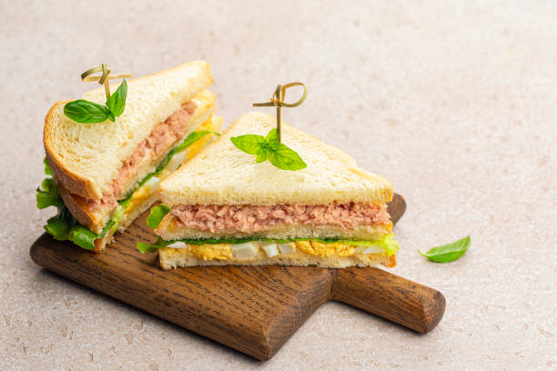 Tuna sandwiches with boiled egg, mayonnaise, lettuce on a wooden board. stock photo