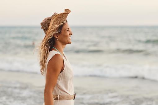 Happy woman with a straw hat enjoying on the beach. Copy space.