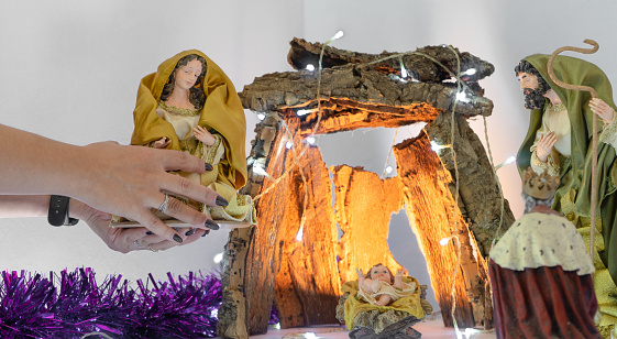 A woman is about to place a figure in the Christmas Manger which is being prepared for Christmas