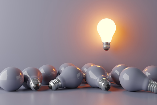 Thinking in a different, innovative and creative way. Finding a bright idea or solution. Individuality, originality, difference and uniqueness. One lightbulb glowing above the others bulbs. 3D rendering.