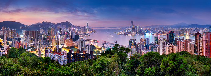 Victoria Harbor in Hong Kong paints a mesmerizing scene, the silhouette of a ferry boat adding charm to the city's twilight beauty.