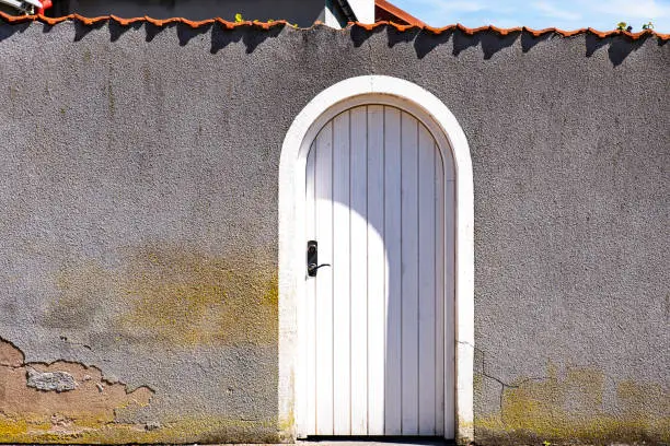 Front view of white arched closed door on worn grey wall represents end of conversation or stop negotiation. Entrance or exit arch with shut wooden gate on gray background conveys denial or stop talk