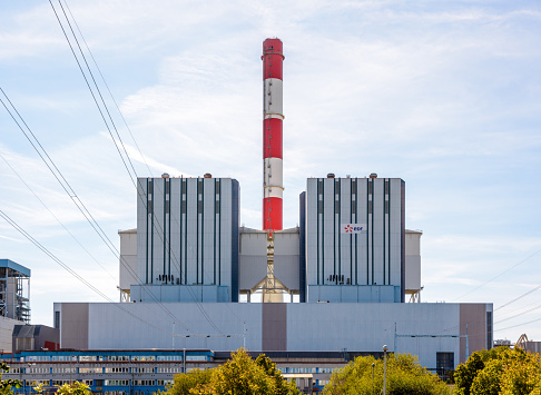 Cordemais, France - September 20, 2022: Front view of the main building of the EDF coal-fired power station of Cordemais, with a red and white chimney, near Nantes, Loire-Atlantique, on a sunny day.