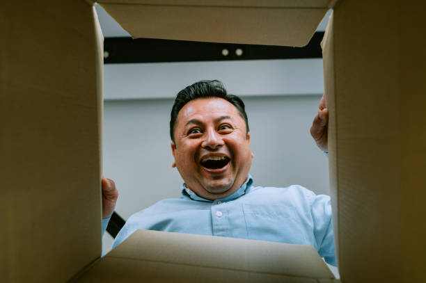 mage of Asian man is opening gift and looking inside cardboard box