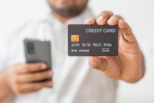 Close-up hand of Asian man wearing white shirt holding black credit card in his hand. isolated on white background. Concept of finance, trading, communication, social, technology, business.