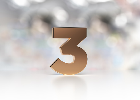 Golden number three is standing on the white desk in front of the bokeh background horizontal composition