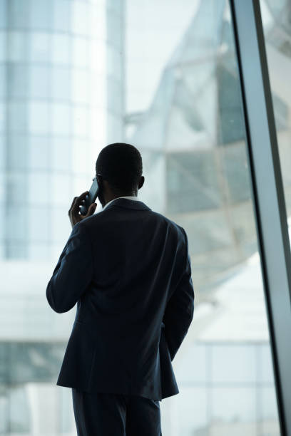 istock Back view of young white collar worker with smartphone by ear in office 1427499186