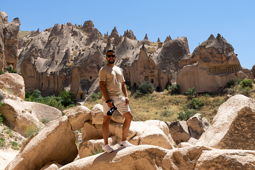 Young male tourist with his camera visiting the fairy chimneys in Cappadocia, Turkey