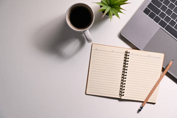 istock Blank notepad, laptop computer, coffee cup and potted plant on white office desk. 1427499734