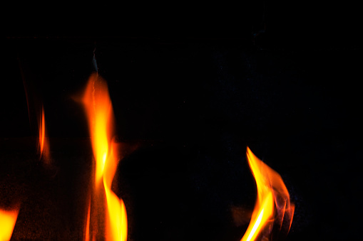 orange flame of fire in the fireplace on a dark background, horizontal