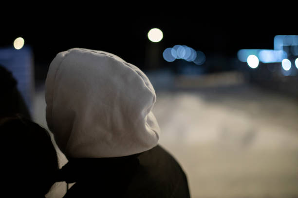Woman taking the dog for a walk at night in Berlin, Germany, during the snowy winter.