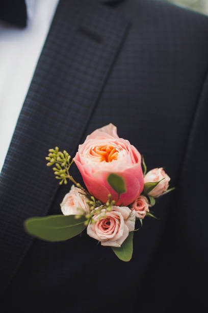 Elegant wedding boutonniere on the groom's suit Elegant wedding boutonniere on the groom's suit. buttonhole flower stock pictures, royalty-free photos & images