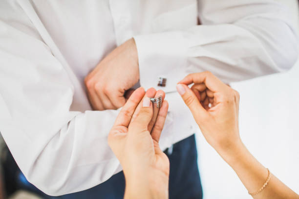 Groom in the morning during wedding preparations. Bride helping groom put on cufflinks