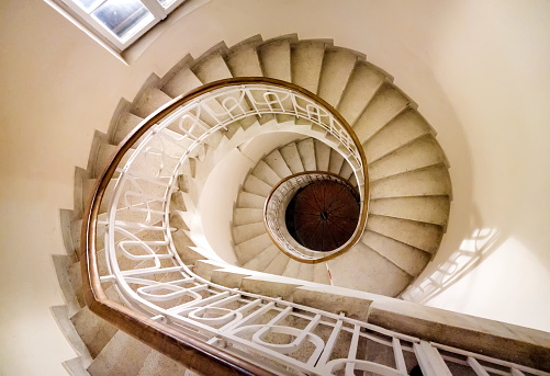 A winding historical staircase with red linoleum lining