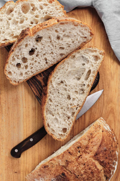 istock Sliced round rustic bread without kneading on a cutting board next to a knife. Homemade whole grain bread, layout on the table, vertical frame 1427511513