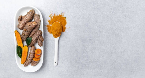 istock turmeric powder in spoon with turmeric root. curcuma or curcumin on concrete background. Spice, natural coloring, alternative medicine. Long banner format. top view 1427516060