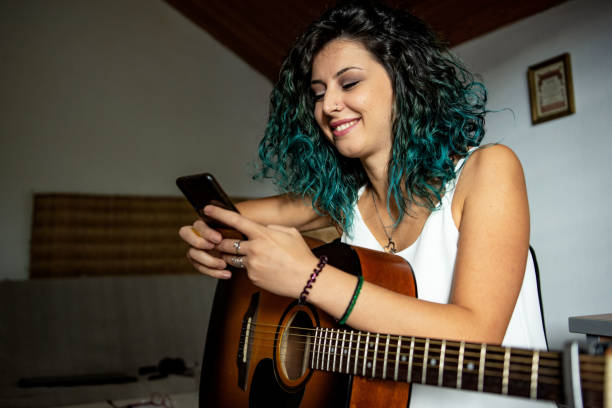 istock Young woman playing a guitar at home 1427516919