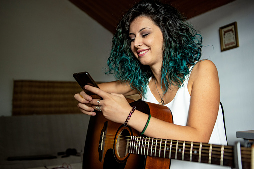 Young woman playing a guitar at home