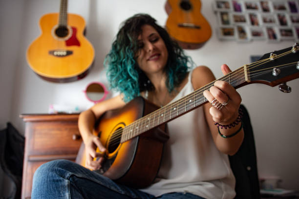 istock Smiling beautiful young woman playing guitar 1427517673
