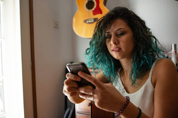 istock Young woman playing a guitar at home 1427518565