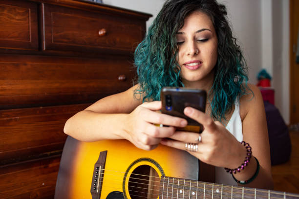 istock Young woman playing a guitar at home 1427519097