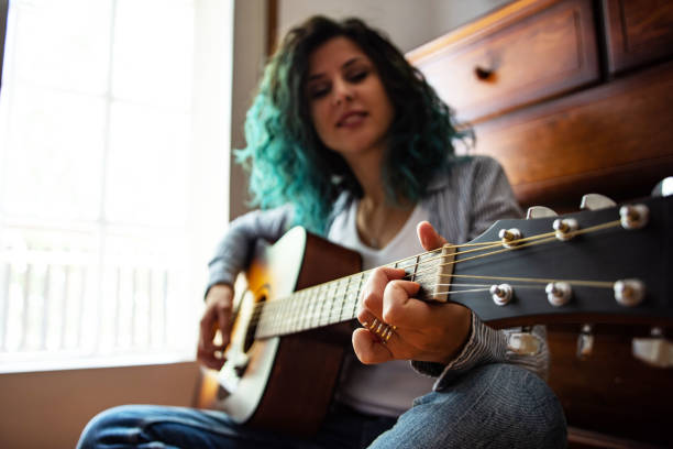istock Smiling beautiful young woman playing guitar 1427519233
