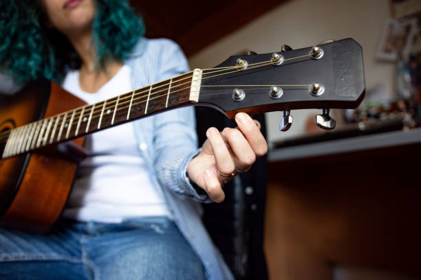 istock Unrecognizable beautiful young woman playing guitar at home 1427519277