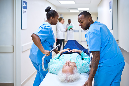 Male and female nurses pushing patient lying on stretcher in hospital