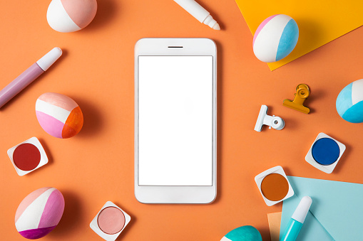 Mobile phone with white screen and easter eggs on orange colored background