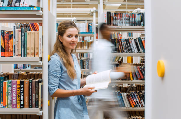 istock Young woman reading a book in the library 1427523774