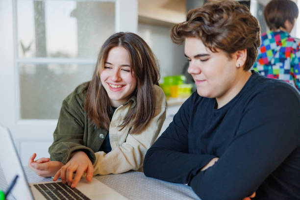 istock Two high school students sitting at the table at home, having fun and using laptop for remote learning 1427527316