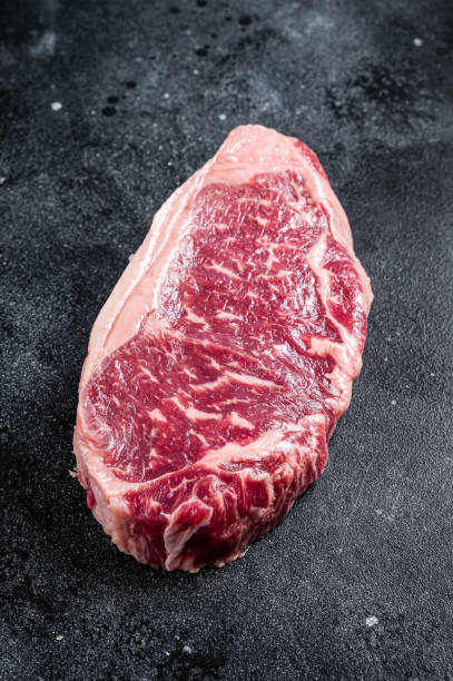 istock Raw Striploin steak, beef butchery cut. Black background. Top view 1427527331