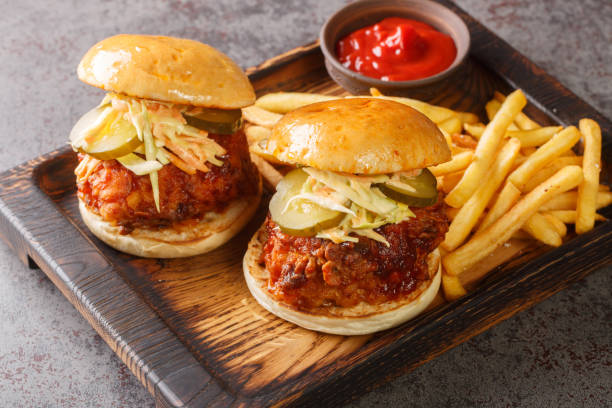 istock Nashville Hot Chicken is a deep-fried chicken slathered in a spicy paste and served on bun with pickles and coleslaw on top closeup on the tray. Horizontal 1427528376