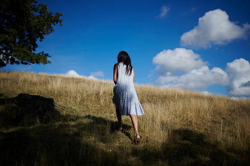 Relaxed Hispanic model outdoors in natural light. Woman walking away full length