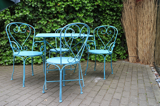 Iron chairs and table on a terrace with a hedge