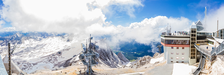 Landscape with cable car station at the summit of Zugspitze, hightest mountain of Germany, with blue sky and clouds, near Garmisch-Partenkirchen, Germany, and Ehrwald, Tyrol, Austria (Panorama)
