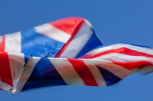 United Kingdom British flag flying in the wind with a blue sky background and copy space