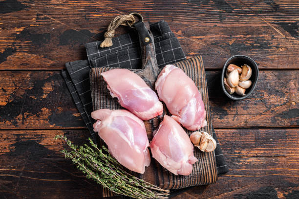 鶏もも肉の切り身、まな板に生の骨なしと皮のない肉。木製の背景。トップビュー - thigh ストックフォトと画像