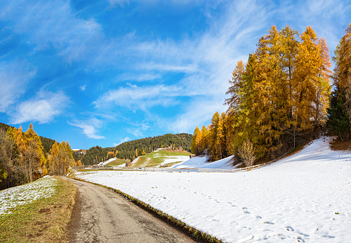 Country road in the mountains on a sunny day in late autumn. South Tyrol, Dolomite mountains, Northern Italy