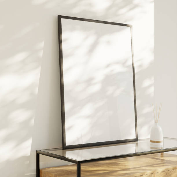 istock Interior mockup - Living room with a blank picture frame on a sideboard leaning against the wall. Luminous pattern light effect. Porcelain vase with room fragrance sticks. 1427531300