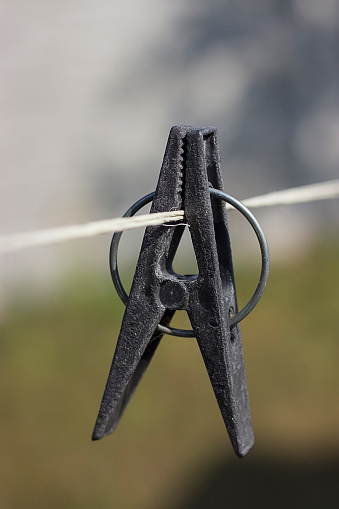 A black clothespin on a clothesline on a sunny day