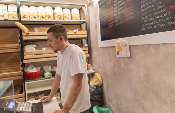 istock Young baker at the cash register making a receipt for a customer 1427531645
