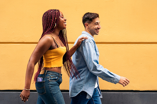 Cute young couple wearing casual clothes having fun in the streets of Madrid and walking.