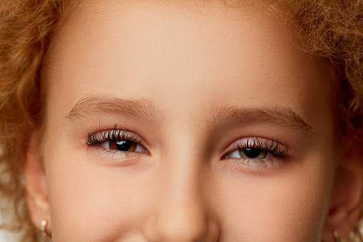 Joyful look. Closeup of little girl's eye with black curly eyelashes. Kids ophthalmology. Children female face with open eyes. Emotions, facial expressions, healthy eyesight. Details