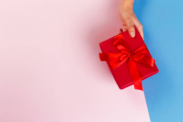 istock Woman holding gift box on color background 1427537074